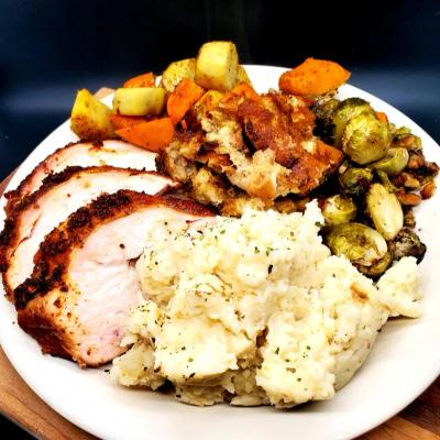 Turkey slices, mashed potatoes, Brussels sprouts, and root vegetables on a plate.