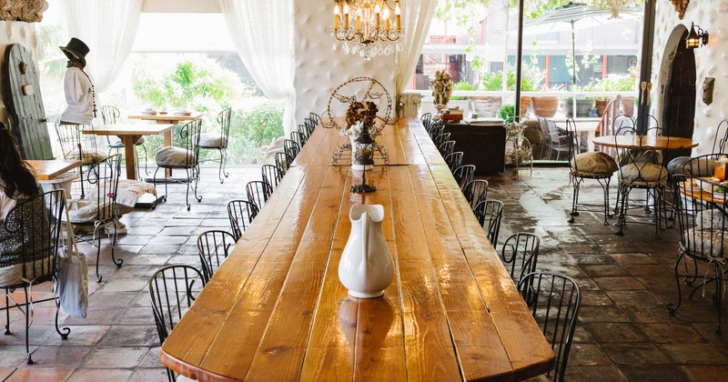 Interior with a large, polished wooden table with numerous black wire chairs