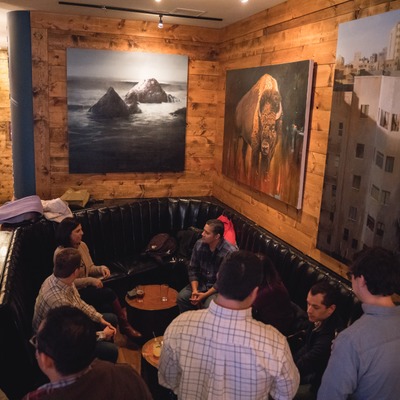 Booth with tables, guests, and wall art in an interior setting.