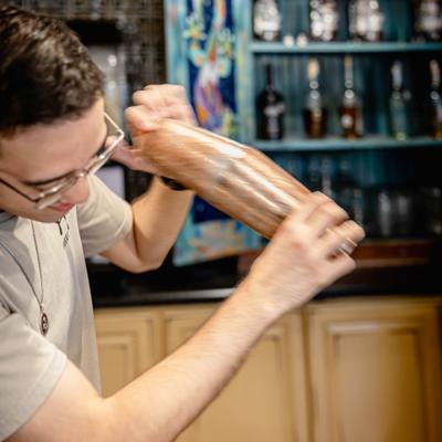 Staff member shaking a cocktail behind the bar.