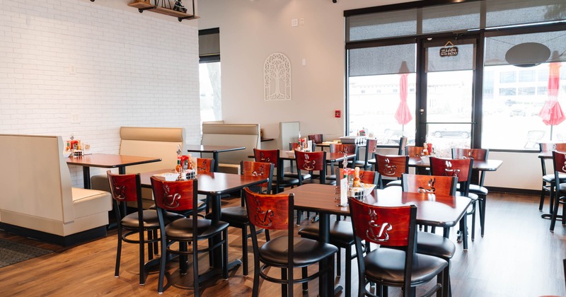 Interior of a restaurant with wooden tables, chairs, and beige booth seating