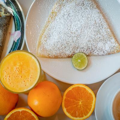 Crepe dusted with powdered sugar, served with orange juice and fresh oranges.