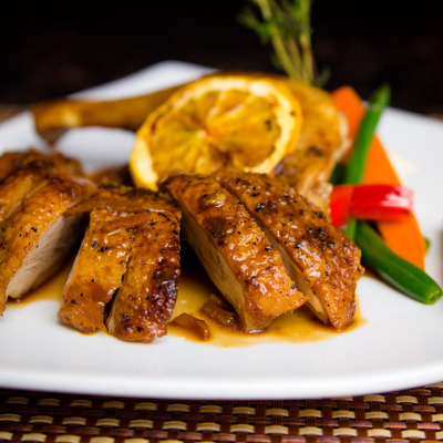 Slices of roasted duck breast with orange sauce and vegetables.