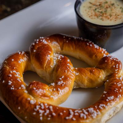 Salted pretzel with cheese dip.