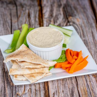 Hummus and pita served with carrot and celery sticks.