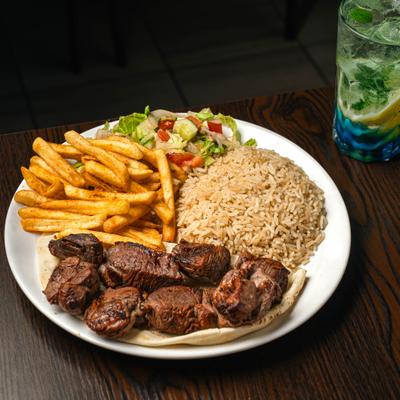 Lamb kebab wrap served with fries, salad, and rice.