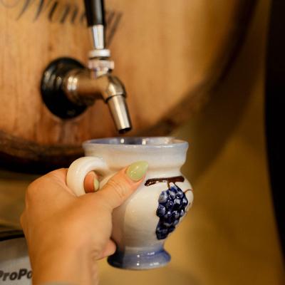 A hand holding a container under a barrel dispensary.