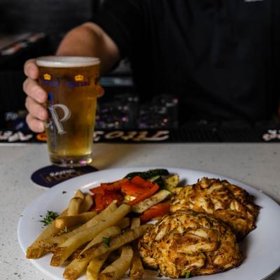 Crab cake platter and a glass of beer served at bar counter