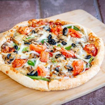 A vegetarian pizza served on a wooden board.