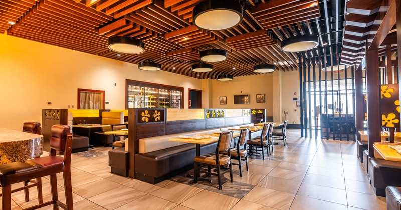 Modern restaurant interior with wooden ceiling slats, plush seating, and warm lighting