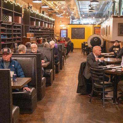 Interior with black booths and wood flooring, patrons enjoying meals and conversing.