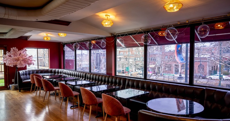 Restaurant interior with black leather seating, pink velvet chairs
