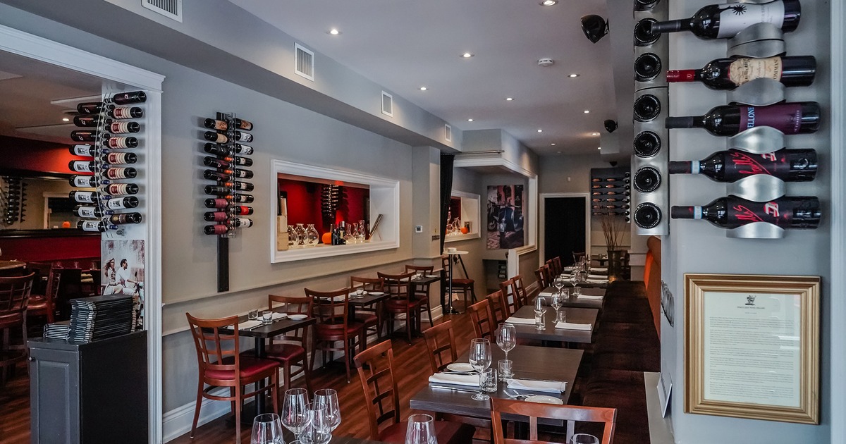 Restaurant interior, dining area with set tables, wall-mounted wine racks