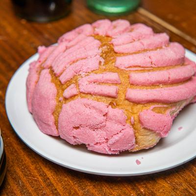 Sweet bread concha with pink topping, close-up.