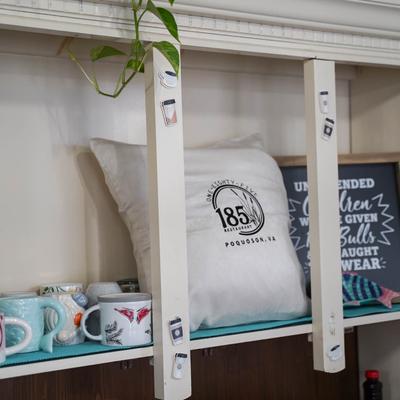 A shelf displaying colorful mugs and a pillow featuring the restaurant’s logo.