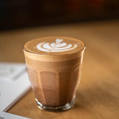Cortado  served in a glass cup with latte art.