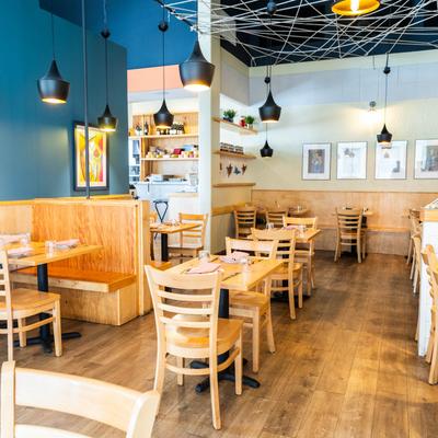 Bright restaurant interior with wooden booths, tables, and wall art.
