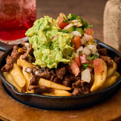 Steak fries with guacamole and pico de gallo, served in a skillet.