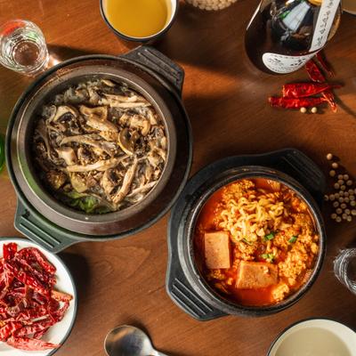 Soft Tofu Stew served alongside Mushroom rice, sides of kimchi and dried chili peppers.