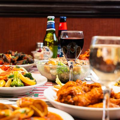 A table full of various dishes, glasses of wine, and bottled beers.