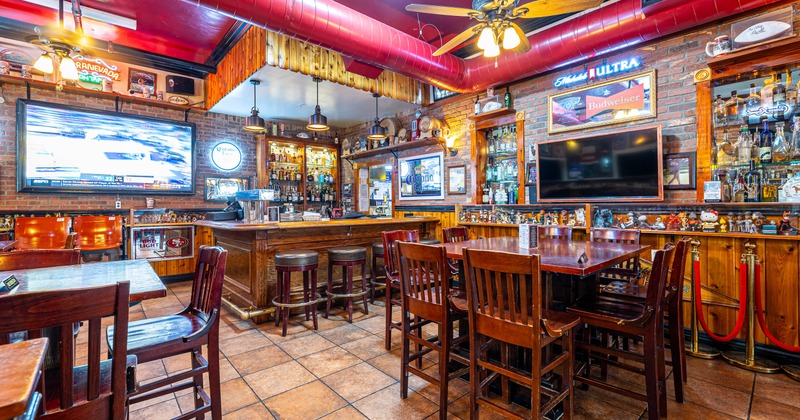 Cozy bar interior with wooden tables and stools, brick walls, and a warm
