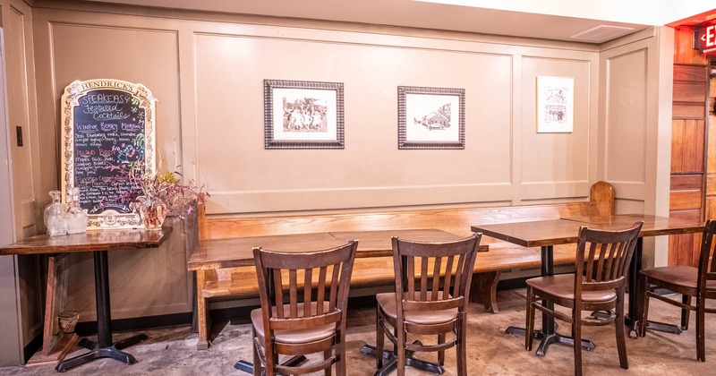 Interior, long wooden banquette bench with four tables and chairs, cocktail menu board