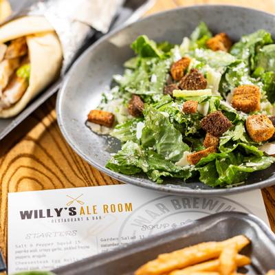 Caesar salad on a table beside a menu.