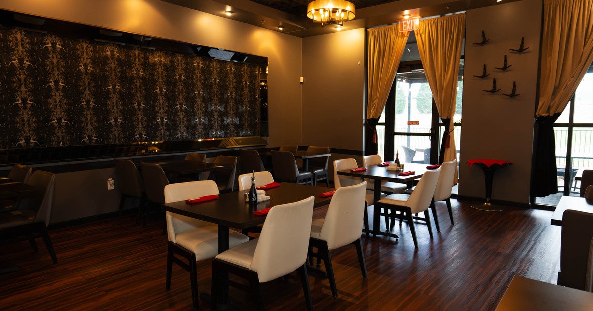 Interior of a modern restaurant with wooden tables, leather chairs, and ambient lighting
