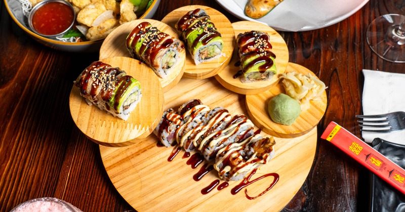 Sushi rolls topped with avocado and sauces