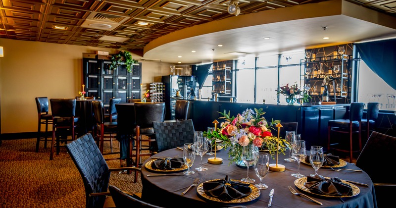 Elegant dining area - black tablecloths, floral centerpieces, black chairs and gold-accented decor