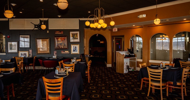 Interior, seating area, tables with chairs, entrance with reception desk, various framed pictures