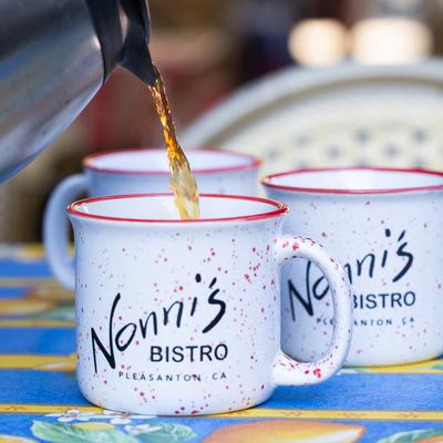 Coffee poured into Nonni's Bistro mugs on a table.