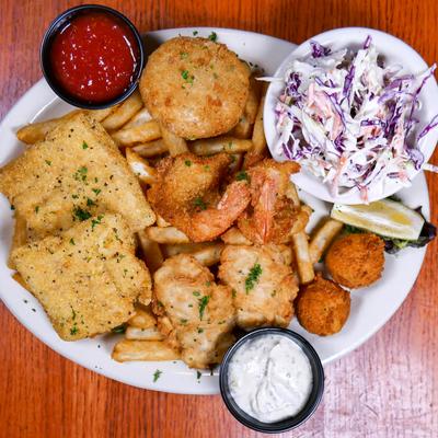 Fried food sampler platter with sauces for dipping and a bowl of coleslaw.
