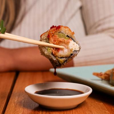 The crunchy roll piece dipped in soy sauce, close up.
