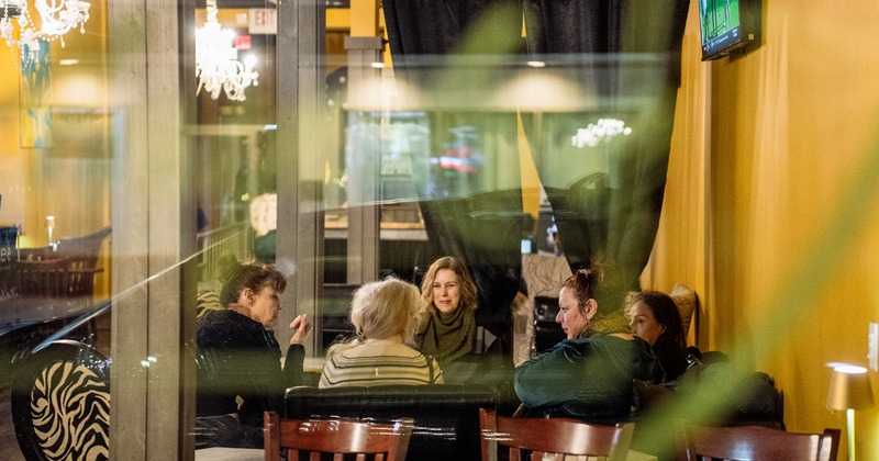 Friend group gathering, seated behind a glass