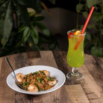 Crawfish etouffee served with shrimp, beside a cocktail.