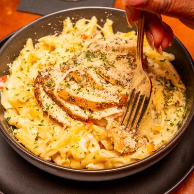 Fork taking a bite of Chicken Alfredo pasta.