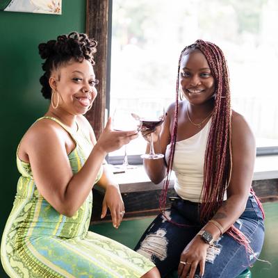 two ladies smiling for the camera holding their wine glasses.