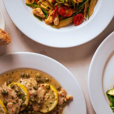 Overhead view of piccata and pasta dishes on a table.