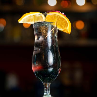 Colorful cocktail with lemon slices on a table, with a blurred background.