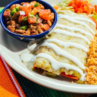 Green enchiladas served alongside rice and a bowl of pinto beans with pico de gallo.