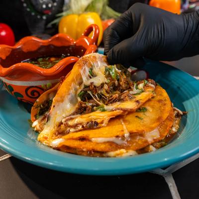 Birria tacos with melted cheese and birria dipping sauce.