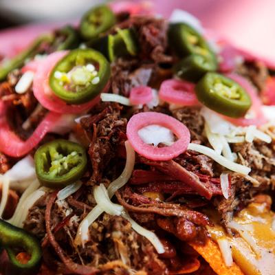 Pulled pork nachos topped with melted cheese, pickled onions, jalapenos, and shredded cheese.
