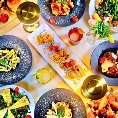 Assorted pasta, salads, and seafood dishes on a table with golden lamps.