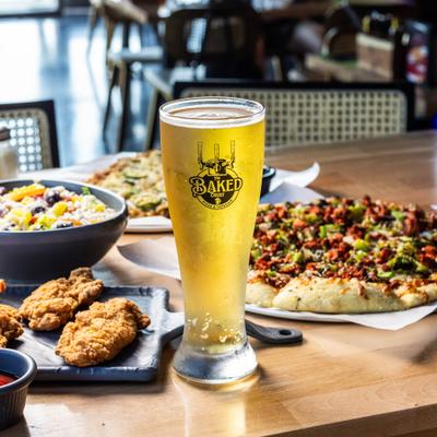 Tall glass of beer served on the table alongside various menu items.