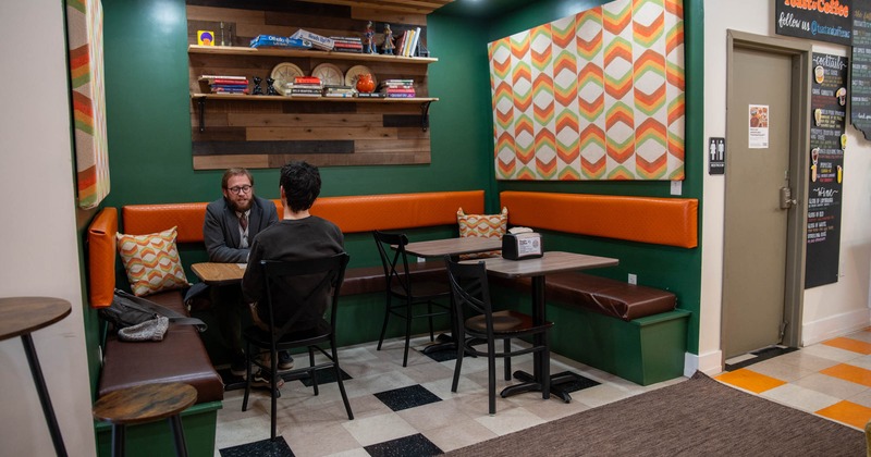 Seating area with tables, colorful geometric wall decor, and two guests