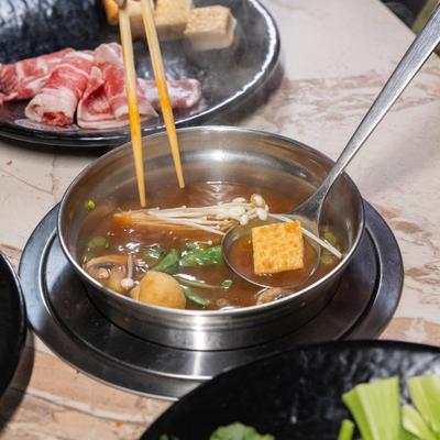 Hot pot with mushrooms, tofu, and vegetables.