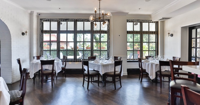 Interior, dining area, tables for four, large windows decorated with small lanterns
