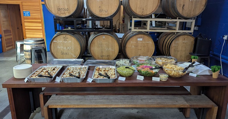 Food on an open table and stacked wooden barrels behind it