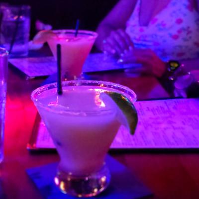 Assorted drinks on a table with guests in the background looking at menus.